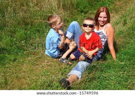 children and mother lie on grass