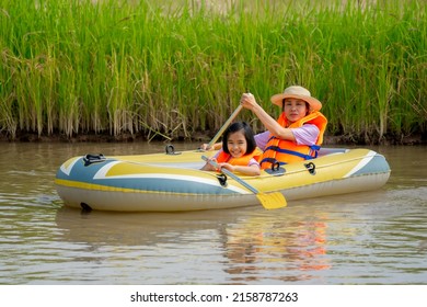children and mother playing and rowing boat in river of countryside for relaxing time in summer season