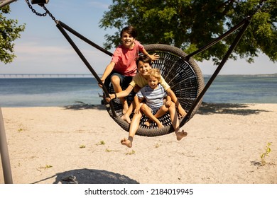 Children On Beach Swing. Kid Swinging In Malmo, Sweden, Travel With Young Children. Summer Family Vacation With Kids Playing  On Sea Shore