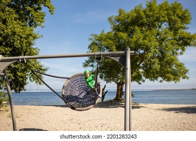 Children On Beach Swing. Kid Swinging In Malmo, Sweden, Travel With Young Children. Summer Family Vacation With Kids Playing  On Sea Shore