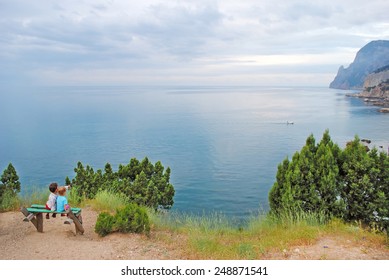 Children on a bench on the seafront overlooking the rocks, ocean and cloudy sky in pastel colors - Shutterstock ID 248871541