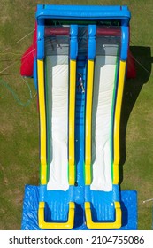 Children On A Giant Inflatable Water Slide In A Home Backyard