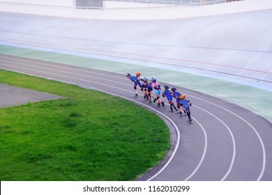 children on rollers in helmets and blue sports suits ride on a racing platform for athletes, sports and recreation

