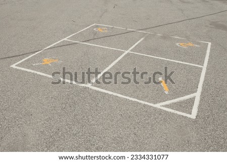 children outdoor four square school yard game printing in white and yellow with one two three four on pavement - one in foreground and three in background