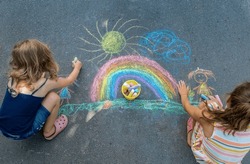 Children Paint A Rainbow On The Asphalt. Selective Focus. Kids.