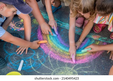 Children paint a rainbow on the asphalt. Selective focus. Kids.