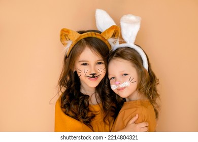 Children with painted faces in rabbit and tiger costumes are hugging and smiling sweetly. The old new year meets the new one. Stage animal costumes.