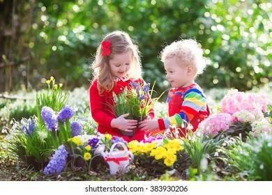 Children Planting Spring Flowers In Sunny Garden. Little Boy And Girl Gardener Plant Hyacinth, Daffodil, Snowdrop In Flower Bed. Gardening Tools And Water Can For Kids. Family Working In The Backyard.