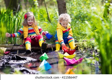 Children play with colorful paper boats in a small river on a sunny spring day. Kids playing exploring the nature. Brother and sister having fun at a forest stream. Boy and girl with toy boat and ship - Powered by Shutterstock