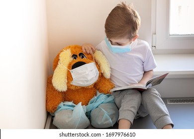 Children Play A Doctor. A Large Brown Toy In A Medical Bandage And Shoe Covers Is Sitting On The Window. A Child Is Reading A Book To His Friend. Two In Medical Quarantine.