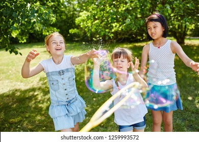 Children play with fragile soap bubbles and have fun in the park