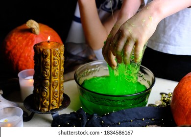 children play with a green witchcraft potion, table is covered with a black cloth, pumpkins lie, animal skulls, candles are burning, the concept of the Halloween holiday, love spell, children's party - Shutterstock ID 1834586167
