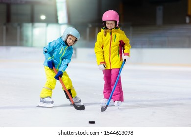 Children Play Ice Hockey On Indoor Rink. Healthy Winter Sport For Kids. Boy And Girl With Hockey Sticks Hitting Puck. Child Skating. Little Kid On Sports Training After School. Snow And Ice Fun.