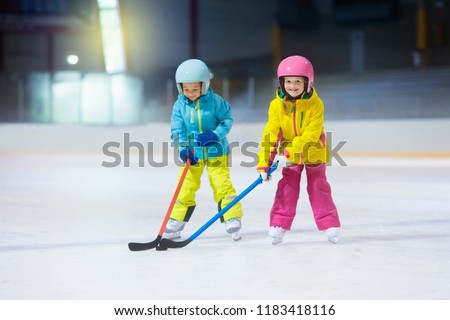 Children play ice hockey on indoor rink. Healthy winter sport for kids. Boy and girl with hockey sticks hitting puck. Child skating. Little kid on sports training after school. Snow and ice fun.