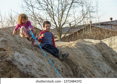 Children Play On The Hill Of Mud With A Dog