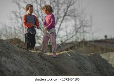 Children Play On The Hill Of Mud With A Dog