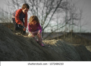 Children Play On The Hill Of Mud With A Dog