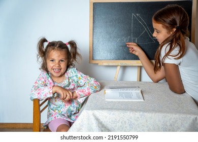 Children play school at home. The older sister prepares the younger sister for school. Preparing to school. Ready to school concept. - Shutterstock ID 2191550799