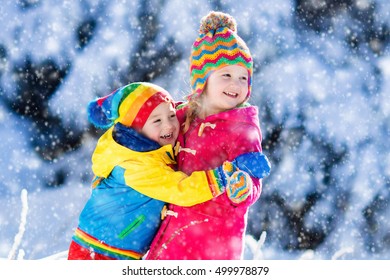 Children Play In Snowy Forest. Toddler Kids Outdoors In Winter. Friends Playing In Snow. Christmas Vacation For Family With Young Children. Little Girl And Boy In Colorful Jacket And Knitted Hat.