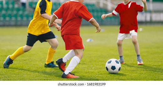 Children play soccer game on grass venue. Kids kicking soccer ball. Boys in red and yellow soccer jersey and soccer cleats - Powered by Shutterstock