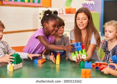 Kinder spielen zusammen mit Bausteinen im internationalen Kindergarten mit einem Kindergartenlehrer