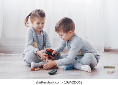 Children Play With A Toy Designer On The Floor Of The Children's Room. Two Kids Playing With Colorful Blocks. Kindergarten Educational Games.