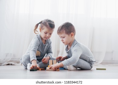 Children Play With A Toy Designer On The Floor Of The Children's Room. Two Kids Playing With Colorful Blocks. Kindergarten Educational Games.