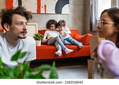 Children Play Video Games On Mobile Phone While Parents Take Personal Stuff Moving In New Apartment Real People Copy Space Caucasian Man And Woman With Siblings