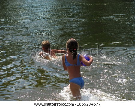 Children play in the water with a ball. The girl catches up with the boy. Beach games