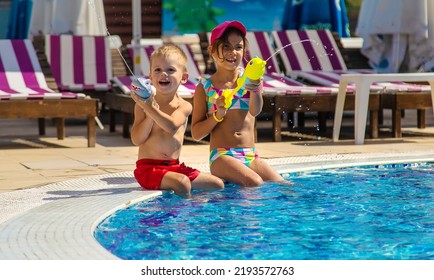 Children Play With Water Pistols In The Pool. Selective Focus. Water.