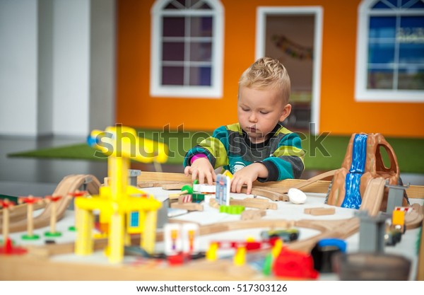 Children play with wooden toy, build toy railroad at\
home or daycare. Toddler boy play with crane, train and cars.\
Educational toys for preschool and kindergarten child. Cushioned\
furniture, chair bag