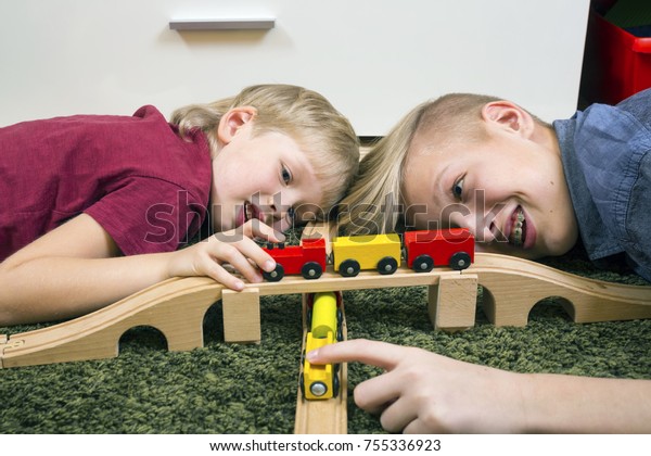 Children play with\
wooden toy, build toy railroad at home or daycare. Toddler boy play\
with  train and cars. Educational toys for preschool and\
kindergarten child. 