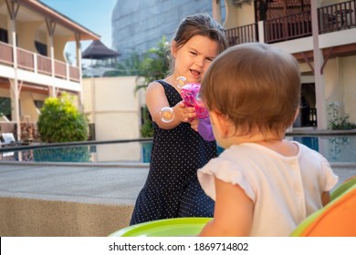 Children Play In The Yard With Soap Bubbles. Baby Girl Playing With Baby Blowing Bubbles