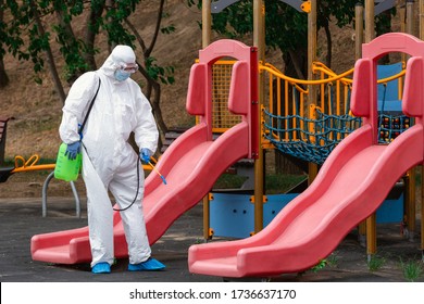 Children playground disinfecting and sanitizing against virus and disease. Man in white protective suit spraying disinfectant on slide to stop 
      spreading coronavirus or COVID-19. Public health. - Powered by Shutterstock