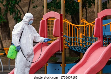 Children playground disinfecting and sanitizing against virus and disease. Man in white protective suit spraying disinfectant on slide to stop 
      spreading coronavirus or COVID-19. Public health. - Powered by Shutterstock