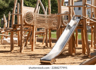 Children Playground with Modern Slide, Rope Net Bridge, Climbing Swings, Climbers. Empty Wooden Playground made of Eco Materials - Wooden Tree trunk Logs Robinia. - Shutterstock ID 2288277991