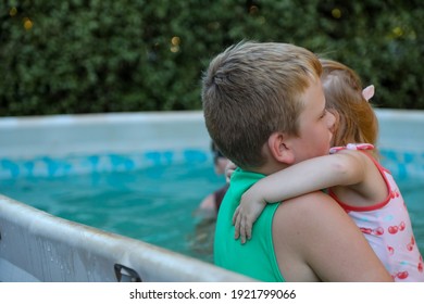 Children Playing In Backyard Above Ground Pool. Big Brother Holding  Little Sister