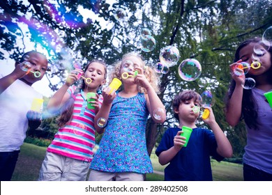 Children playing with bubble wand in the park on a sunny day