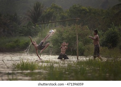 Children Playing Football on water in rural. (Focus on the ball to kick.)