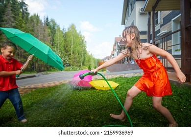 Children playing with garden sprinkler. Brother and sister running and jumping. Summer outdoor water fun in backyard. Boy and girl play with hose watering grass. Kids run and splash on hot sunny day