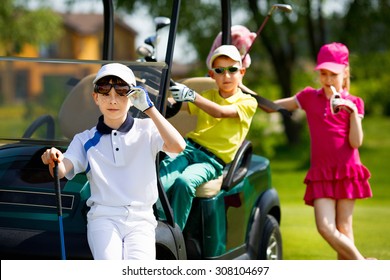 Children playing golf and taking part on kids competition in golf course at summer day
