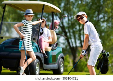 Children playing golf and taking part on kids competition in golf course at summer day