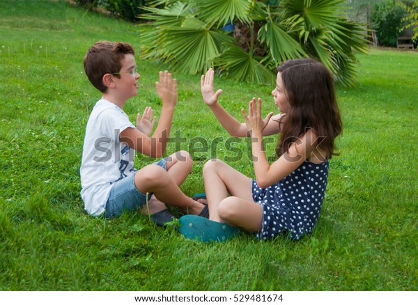 Children playing hand\
clapping game outdoors