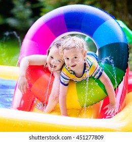 Children Playing In Inflatable Baby Pool. Kids Swim And Splash In Colorful Garden Play Center. Happy Boy And Girl Playing With Water Toys On Hot Summer Day. Family Having Fun Outdoors In The Backyard.