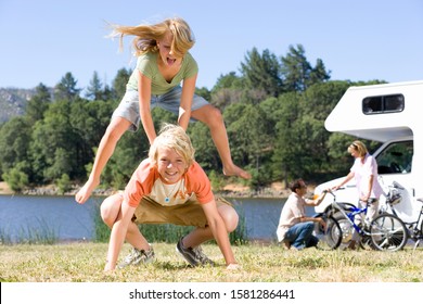 Children playing leapfrog in countryside on motor home vacation