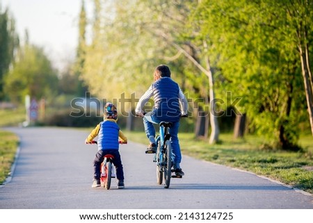 Children, playing on the street with blooming pink cherry trees on sunset, riding bikes