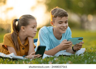 Children playing online video games with their friends on cell phones outdoors in summer park. - Powered by Shutterstock