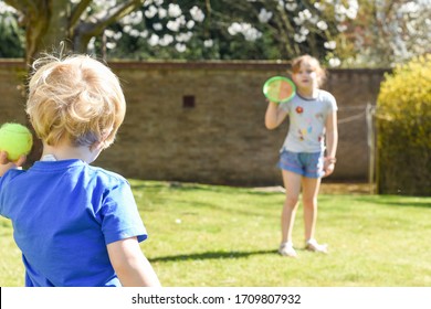 Children playing outside a brother and sister play a ball game in a garden