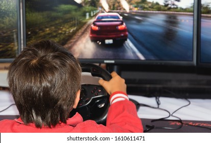 Children Playing Pc Game On A Computer. Young Man Playing Car Race Game With Steering Wheel. Children Playing Car Racing Game On A Video Game.