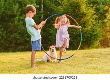 Children playing with pet dog jumping through hula hoop - Shutterstock ID 2281709251
